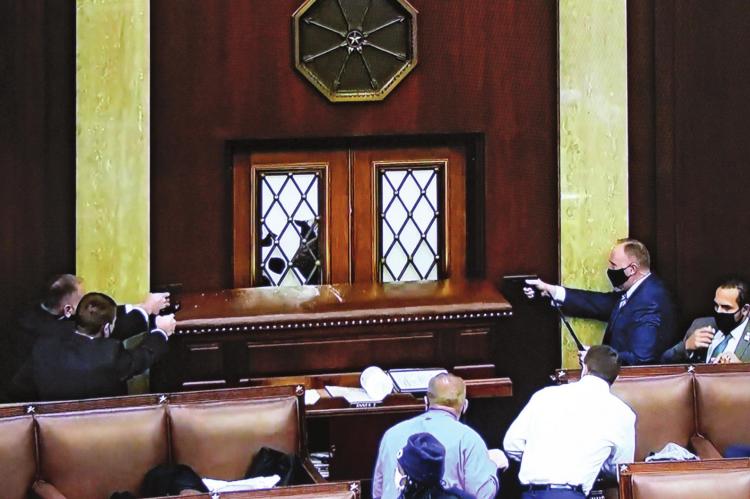 INSIDE THE U.S. HOUSE, law enforcers draw sidearms to prevent entry by insurrectionists.
