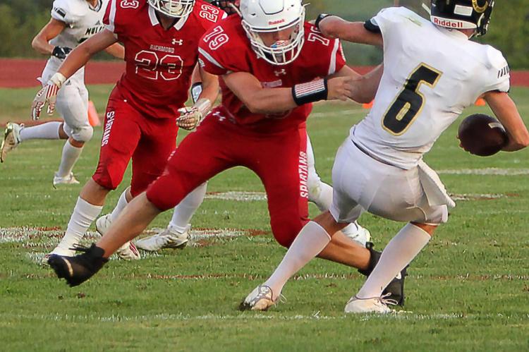 RICHMOND’S ZAIN WETTENGEL, a senior defensive lineman, forces Lathrop quarterback Mason Adwell to retreat.
