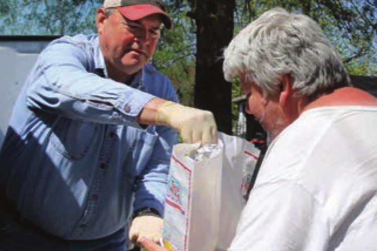 COMMISSIONER Allen Dale delivers bags of food to Jonathon Reavis. The Ray County Senior Center makes home deliveries to make sure older residents can get food after the center closes because of COVID-19.