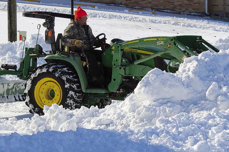 A CITY WORKER pushes snow onto the corner of West North Main and North Camden. SHARON DONAT | Staff