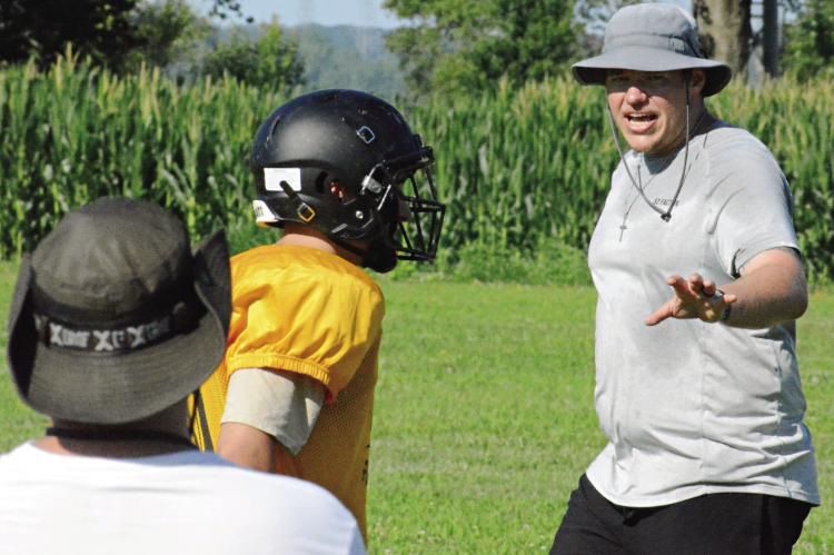 ORRICK ASSISTANT COACH Chase Sims (right) explains assignments and techniques as the Bearcats install their new defense during varsity team camp Monday on the Orrick practice field. SHAWN RONEY | Staff