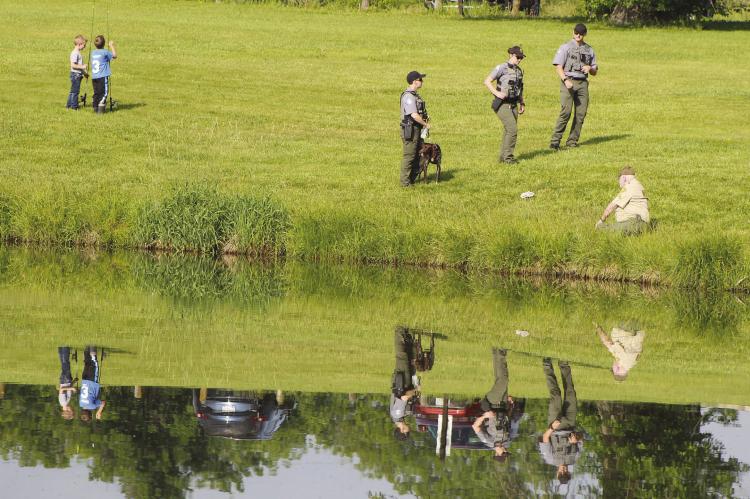 REFLECTIONS RIPPLE ACROSS the pond as children, conservation staff and first responders spread out along the shoreline for a morning of fishing and outdoor activities. SHARON DONAT | Staff