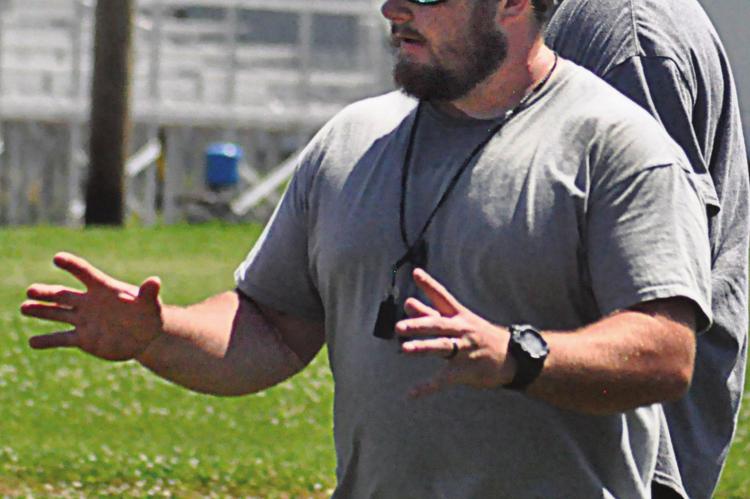 SPORTING HIS shades, ballcap and whistle, first-year varsity head coach Andrew Watson explains blocking assignments to his Aggies during Norborne Hardin-Central’s team camp for 8-man football. SHAWN RONEY | Staff