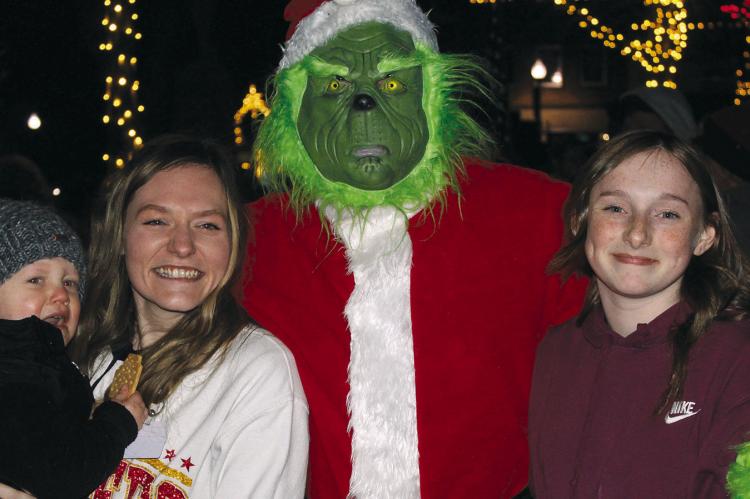 WHILE SNEAKING around the square, the Grinch stops for a photo opportunity with Elijah and Amanda Hall (left) and Daysyn Miller. SHARON DONAT | Staff