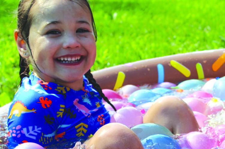 RYAN JONES takes a break in a pool full of water balloons during the CAP water balloon fight in the park. SHARON DONAT | Staff