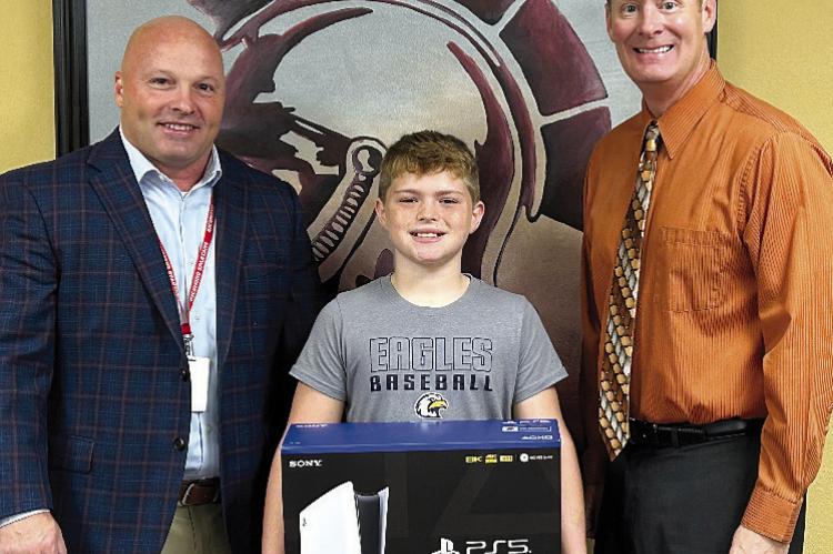 RICHMOND SCHOOL District Assistant Superintendent Trey Cavanah (left) and Superintendent Dr. Bryan Copple (right) present the PS5 to raffle winner Jaxx Hicks. Submitted