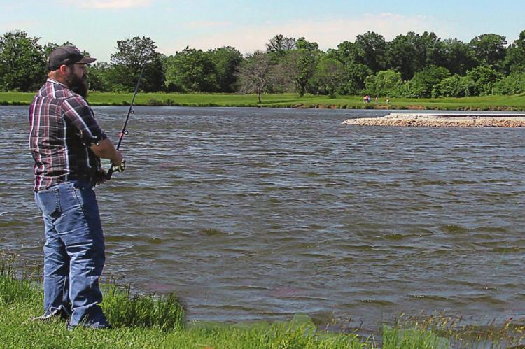 ON THE EAST SIDE of Ray County Lake, David Wratt, Richmond, fishes. In the background is evidence of work to improve lake facilities, which will include improved parking and new restroom facilities.