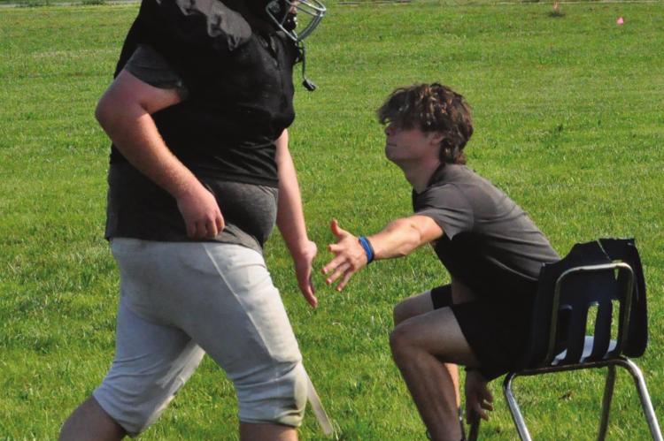 SENIOR BRAYDEN SCHICK gives a low-five to Norborne Hardin-Central teammate Carson Penny while Penny runs wind sprints Monday. SHAWN RONEY | Staff