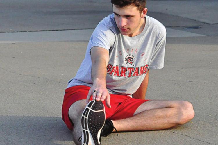 SHELDON GOEDEKE stretches Aug. 17 in preparation for cross country season. SHAWN RONEY | Staff