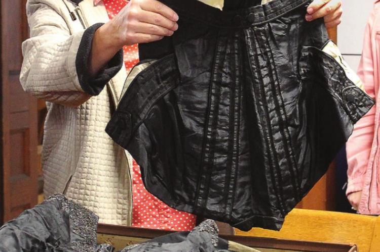 MUSEUM ADMINISTRATOR Cathy Gottsch looks over 19th-century clothing donated to the museum by Public Administrator Shannon Wollard. J.C. VENTIMIGLIA | Staff