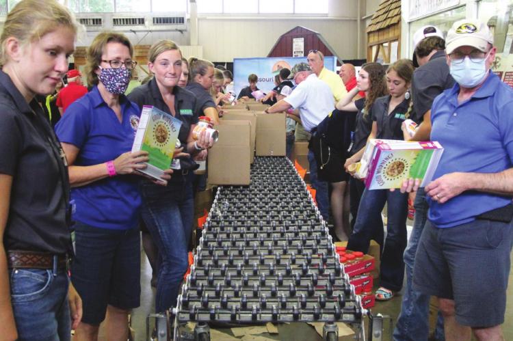 AT THE MISSOURI State Fair, at the front, left and right, are Isabella Kamler and Mark Gunby. They pack boxes for Missouri families in need of food. J.C. VENTIMIGLIA | Staff