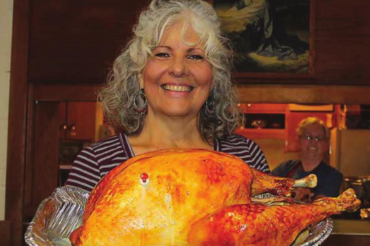 ELEANOR COVEY holds a ready-to-carve turkey pulled fresh from the oven for the Nov. 28, drivethrough community dinner made possible by the cooperative efforts of leaders and members of the Assembly of God, St. John Christian Methodist Episcopal and New Beginnings churches.
