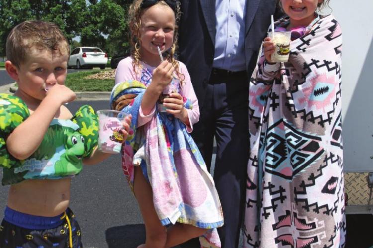 FREE ice cream for everyone at the Higginsville pool is gobbled by Dax Plymell, 4, and his sisters, Ellie Ryun, 6, and Marley Plymell, 6. Behind them, U.S. Rep. Emanuel Cleaver II pays for the ice cream while making sure parents know there is money in the mail coming for school-age children. J.C. VENTIMIGLIA | Staff