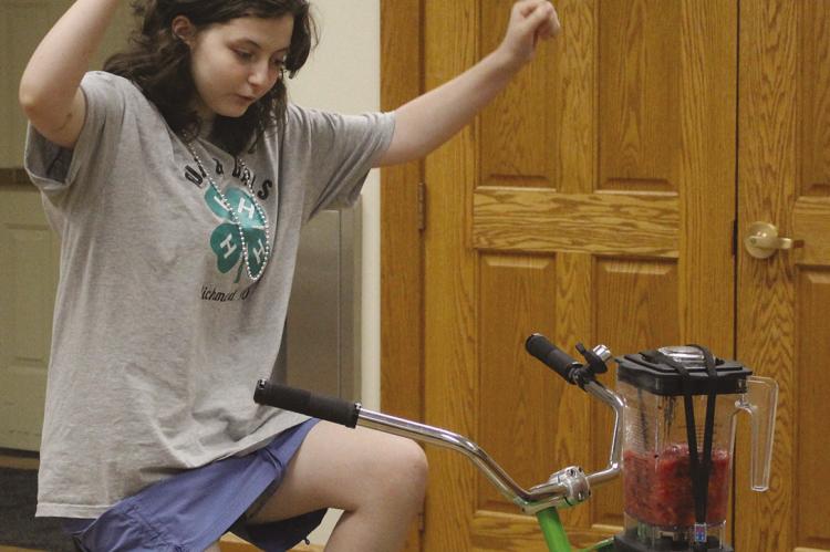 ELSIE ARNOLD pedals a bicyclepowered blender during a recent 4-H program, demonstrating the use of humanpowered energy to make a fruit smoothie. SHARON DONAT | Staff