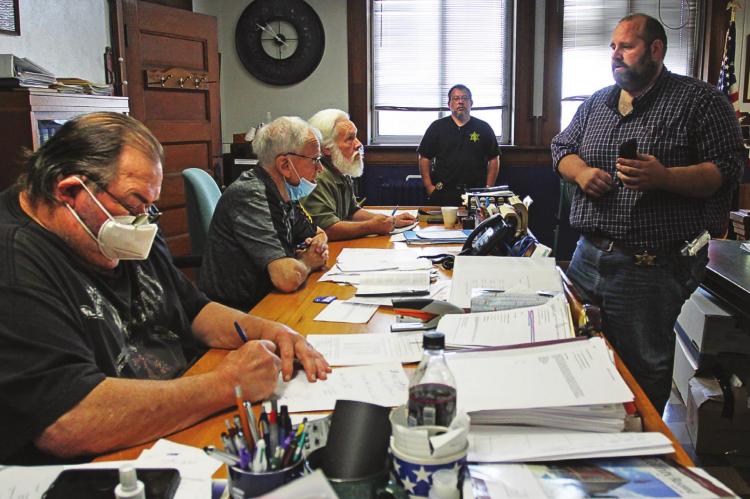 COMMISSIONERS, from left – Gary Wilhite, Bob King and Dave Powell – listen as Sheriff Scott Childers shows cell phone photos of another jail escape attempt made about three weeks earlier. While Childers speaks, Wilhite crunches numbers related to the cost of housing inmates elsewhere to address health and safety issues presented by the jail in Henrietta. J.C. VENTIMIGLIA | Staff