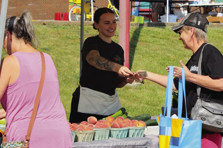 BEV HOLLOWAY purchases peaches at Summer Bash. SHARON DONAT | Staff