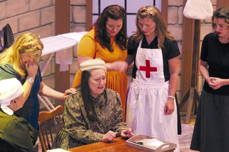Crying at the desk is Cindy Sause (center), surrounded by Jolene Martens (from left), Debbie McGrane, Lacie Bozarth, Annie Quick and Danielle Green. All are in character for the spring play at the Farris Theater. SOPHIA BALES | Staff