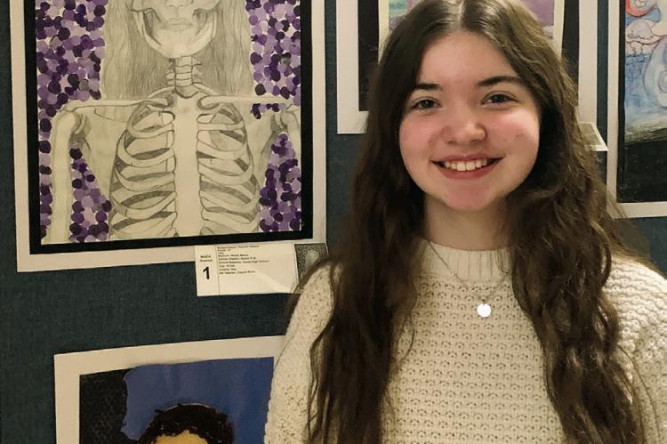 HANNAH ADAMS stands near her altered selfportrait that was inspired by her career goal, medicine. Adams said being able to showcase her art was inspiring.