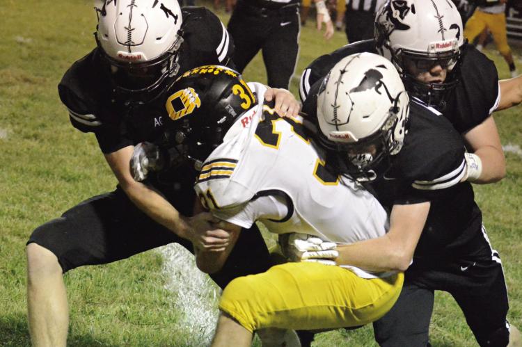 BEFORE BEING crowned a homecoming king, Kalel Bowman (No. 1) helps his fellow Aggies take down Orrick ballcarrier Jeff Rohde. SHAWN RONEY | Staff