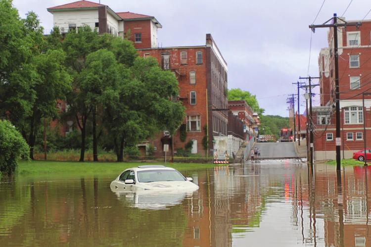 THIS VEHICLE’S DRIVER says he enters a dry Marietta Street, but water climbs quickly from the adjacent river as he travels along the street and strands him before he reaches the bridge less than 100 yards away on June 25, 2021, Excelsior Springs Mayor Sharon Powell tells the Ray County Commission on Monday.