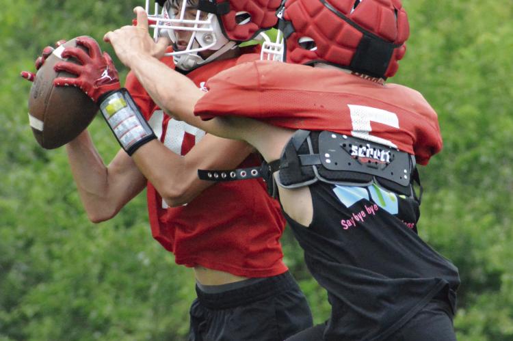 BAYLON CASTILLEJA uses his height to shield the ball from Bryer Farnan and make a two-handed catch while running through passing drills during Richmond’s team football camp session Monday at Richmond High School. SHAWN RONEY | Staff