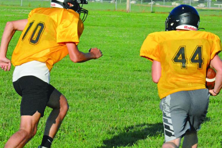 PARKER FLOYD (left) pursues running back Ozzden Ayers as Orrick runs through the circle drill during an offseason camp session. SHAWN RONEY | Staff
