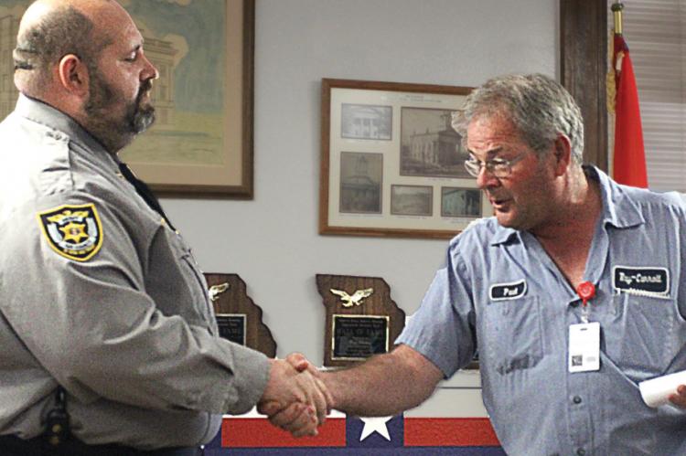 THEY AGREE to disagree, with Sheriff Scott Childers shaking hands with 911 Board President Paul Harris at the end of the County Commission meeting. Childers wants the public to vote to give his office 40% of the tax money now going to 911 so that he can build a county justice center and increase staff.