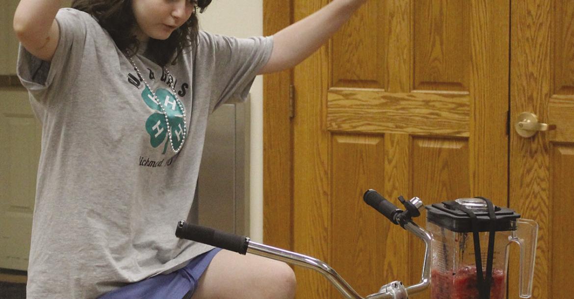 ELSIE ARNOLD pedals a bicyclepowered blender during a recent 4-H program, demonstrating the use of humanpowered energy to make a fruit smoothie. SHARON DONAT | Staff