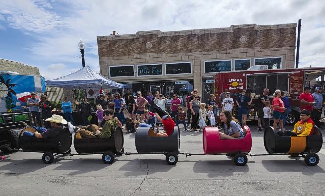 LOCAL CHILDREN are pulled through the parade route by a John Deere Gator. MIRANDA JAMISON | Staff