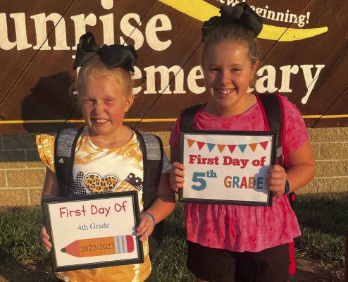 ANNA AND ABIGAIL GARLAND stand ready with their firstday- of-school signs Wednesday at Sunrise Elementary.
