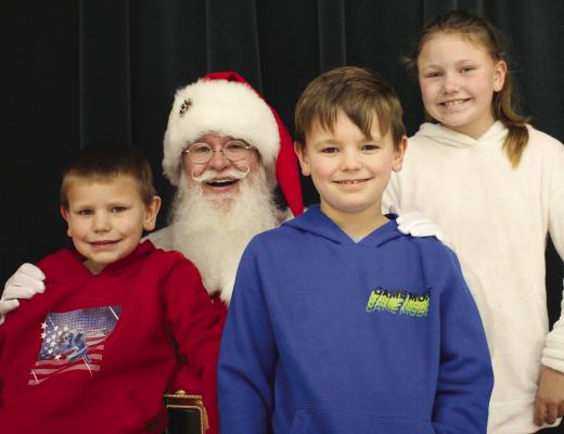 SIBLINGS MICHAEL (from left), John Jr. and Melody Powell sit with Santa at Richmond Middle School last week. SOPHIA BALES | Staff