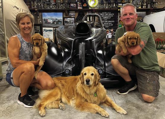 BUSINESS OWNERS Vicki and Paul Comeau with their golden retrievers, Quinn, Clementine and Rocket, sit in front of a Darth Vader-themed race car. The Comeaus are excited to live in Richmond. SOPHIA BALES | Staff