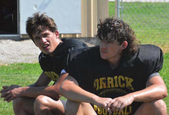 ZANDER STEVINSON, left, and Jaxon Miller take a breather during Orrick’s June 16 8-man football camp session on the Orrick practice field. SHAWN RONEY | Staff