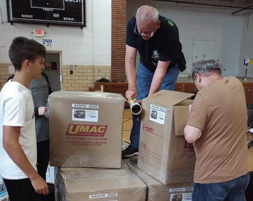 Vince Broker (on top of the box) and other volunteers water-proofing boxes full of Bibles. DAVE DONALDSON | Staff
