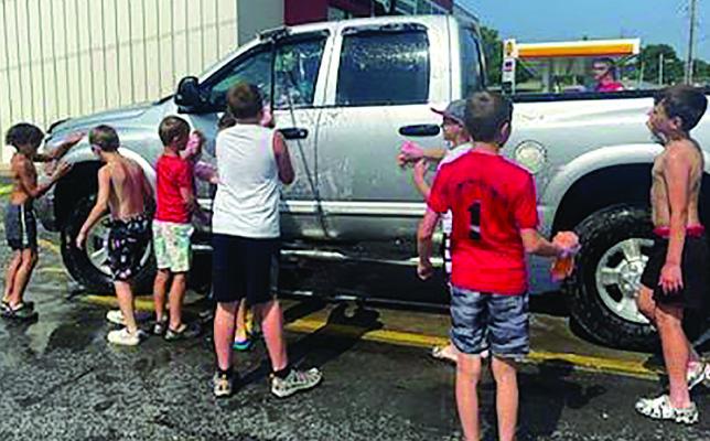 IMPACT baseball boys get wet in their swim trunks as they wash a truck for a good cause.