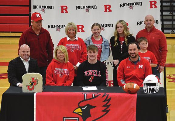 SENIOR LAYNE CAVANAH, front row-third from left, enjoys the moment of signing his letter of intent to play football for William Jewell College in Liberty with his family and Richmond varsity coach Nick Persell, seated next to him. SHAWN RONEY | Staff