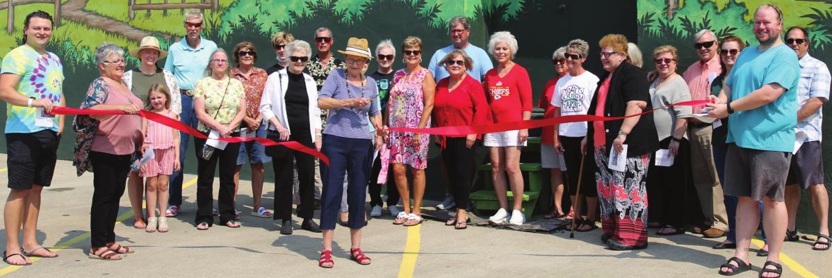 RAY COUNTY artist Patricia Pierce, who did the sketch that led to the mural, cuts the ribbon to dedicate the work of art officially in downtown Richmond.