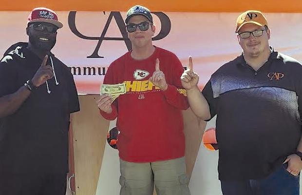 TODD MCCANT (from left) and Chris Battagler win first place at the Community at Play’s (CAP) Lawson Cornhole Tournament. CAP Implenter Alexander Hays provided the winner’s prize. Submitted