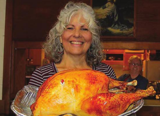 ELEANOR COVEY holds a ready-to-carve turkey pulled fresh from the oven for the Nov. 28, drivethrough community dinner made possible by the cooperative efforts of leaders and members of the Assembly of God, St. John Christian Methodist Episcopal and New Beginnings churches.