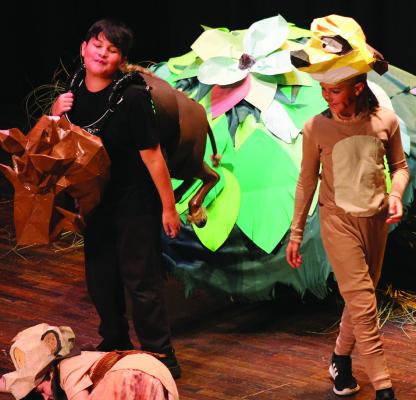 MAVERICK PIERSON (left) and Gabe Rodenberg play Pumba and Timon. The duo looks upon Elijah Durham (on floor) who plays young Simba in scene nine.