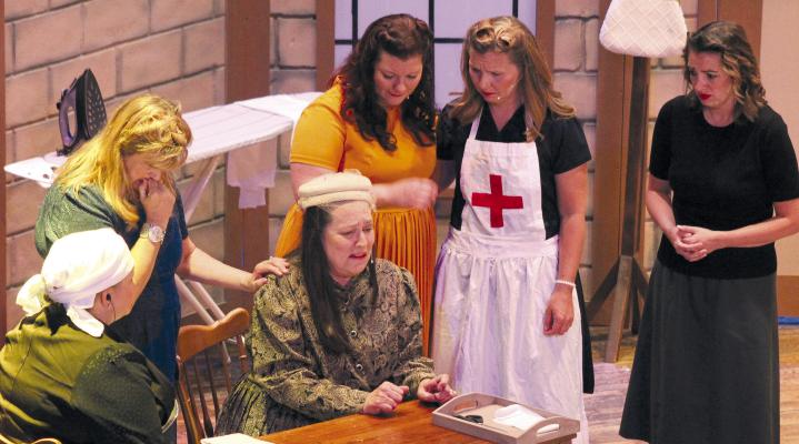 Crying at the desk is Cindy Sause (center), surrounded by Jolene Martens (from left), Debbie McGrane, Lacie Bozarth, Annie Quick and Danielle Green. All are in character for the spring play at the Farris Theater. SOPHIA BALES | Staff