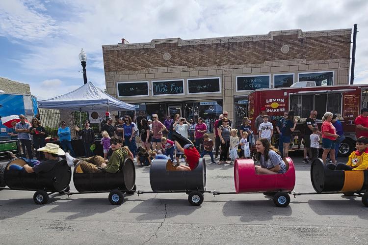 LOCAL CHILDREN are pulled through the parade route by a John Deere Gator. MIRANDA JAMISON | Staff