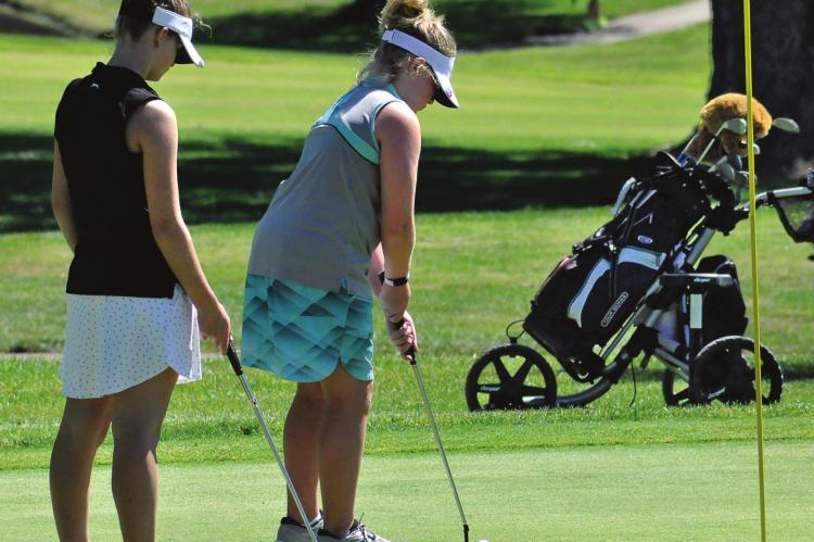 ISABELLE DOOLEY watches her kid sister, Karoline, putt as the girls play June 11 in their first-ever golf tournament. SHAWN RONEY | Staff