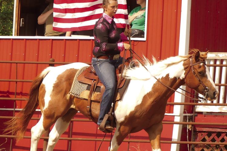 Alexis Reeves carries the American Flag with her horse, Hank, while guests stood for the National Anthem.