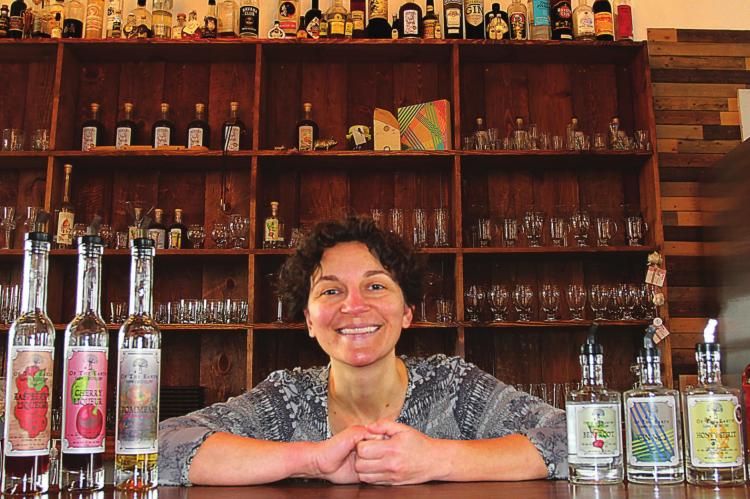 AT THE TASTING BAR, Sarah Burnett-Pierce stands ready with samples and bottled spirits for sale at Of the Earth Farm and Distillery. J.C. VENTIMIGLIA | Staff