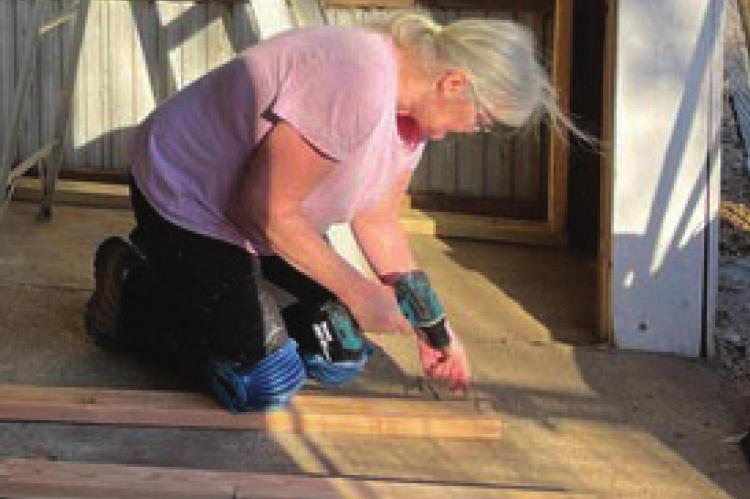 WORKING on the floor in the expanding facility, volunteer Gina Harmon, Richmond, helps out at Autumn Acres Animal Rescue.