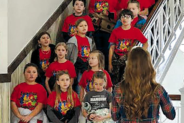 SUNRISE STUDENTS entertain the town of Richmond with songs recently, sparking Christmas spirit not only at the Ray County Courthouse (shown here) but also at the senior center and around the town square. Music teacher Kaelyn Rich guides and instructs the caroling on the chilly morning. BILLY GAINES | Submitted