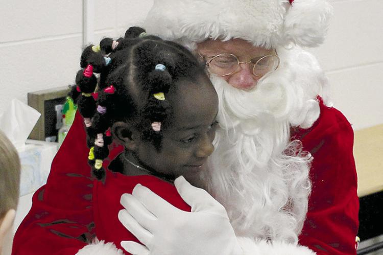 SOPHIA BALES | Staff RIVER SISSON-DODSON hugs Santa Claus as her classmates make their way back to their classroom after story time.