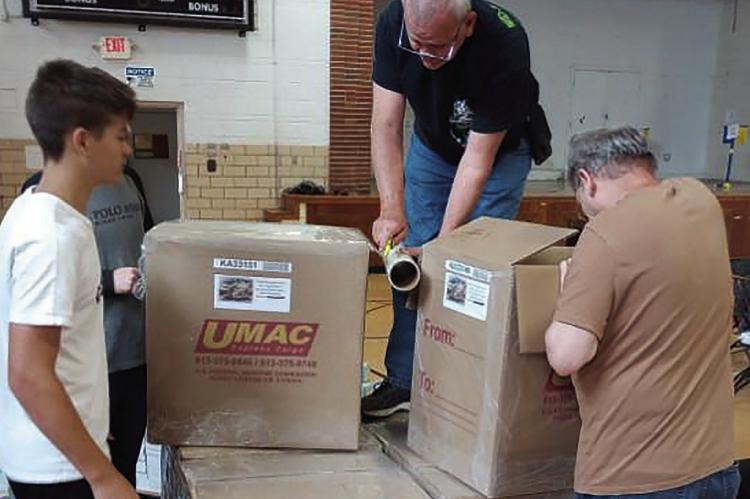 Vince Broker (on top of the box) and other volunteers water-proofing boxes full of Bibles. DAVE DONALDSON | Staff