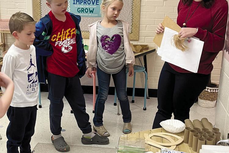 COOPER TRINDLE (from left), Remy Judd, Natilynn Stephens and Dear Elementary technology teacher Brittany Vest look through materials to make ‘zip lines’ through a STEM curriculum formatted by Vest. The first-graders are excited to start the designing process. SOPHIA BALES | Staff